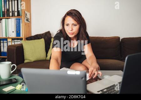 Selbstbewusste Freiberuflerin, die von zu Hause aus mit einem digitalen Tablet arbeitet Im Wohnzimmer Stockfoto