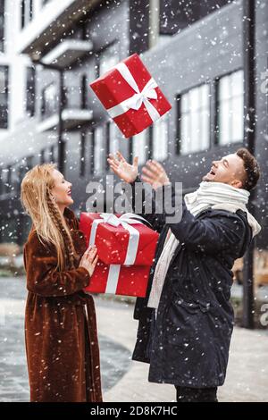 Winter, Urlaub, Paar, Weihnachten und Menschen Konzept - lächelnder Mann und Frau in Winterkleidung mit roten Geschenkschachteln. Stockfoto