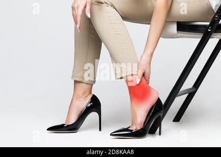 Müde Frau berührt ihren Knöchel, leiden unter Beinschmerzen wegen unbequemen Schuhen, Füße Schmerzen tragen hohe Ferse Schuhe. Syndrom der Büroarbeit. Anschwellen Stockfoto