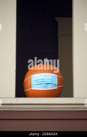 Vancouver, Kanada. 30. Oktober 2020. Auf der Veranda eines Hauses in Vancouver wurde ein Halloween Kürbis mit Schutzmaske platziert. Dieses Jahr hat das British Columbia Center for Disease Control (BCCDC) Kindern, die Trick-or-Treating sind, geraten, in kleinen Gruppen zu bleiben und zu versuchen, nicht-chirurgische Masken in ihre Kostüme zu integrieren, um die Ausbreitung der COVID-19-Pandemie zu verhindern. Stockfoto