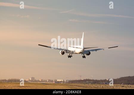 Flugzeug landet am Flughafen an sonnigen Tagen, Rückansicht. Silhouette von Passagierflugzeugen landete fast auf der Start- und Landebahn. Urlaub, Flugkonzept Stockfoto