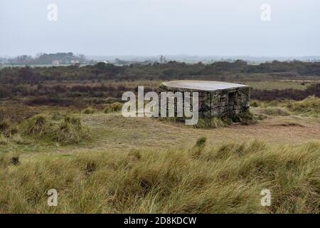 Ein zwei-Säulen-Kasten aus dem Weltkrieg, der sich an einem bewölkten und regnerischen Tag auf den Horsey-Dünen befindet. Die Landschaft von Norfolk erstreckt sich in die Ferne. England. Stockfoto