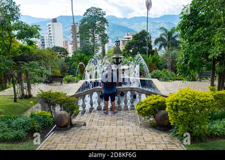 MEDELLIN, KOLUMBIEN - 18. Nov 2019: Medellin, Kolumbien - 17 2019. November: Junger Mann schaut auf einen Brunnen mit grünen Gärten um ihn herum im Schloss Mus Stockfoto