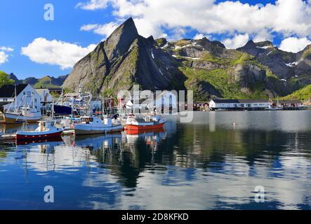 Scharfe Berge und Fischerboote spiegeln sich in den Fjord in Hamnoy, Lofoten Inseln, Norwegen Stockfoto