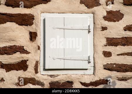 Kolonialer Fensterrahmen mit Fensterläden in Steinmauer Stockfoto