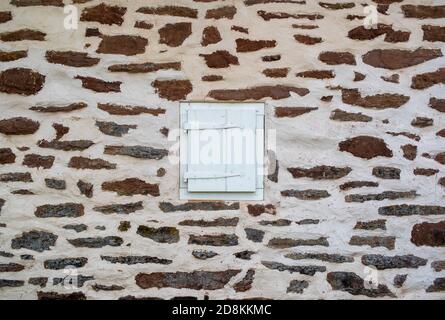 Weißes Fenster mit Holzfenster in einer Steinmauer Stockfoto