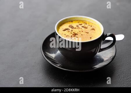 Servieren von aromatischem Kurkuma schwarzen Kaffee gegen dunklen Tisch Stockfoto