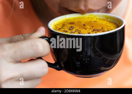 Person genießen Tasse Kurkuma schwarzen Kaffee im Café Stockfoto