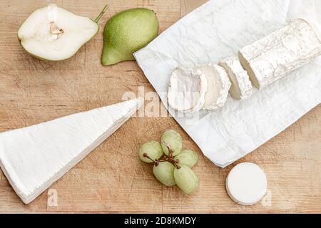 Frischer Käse mit Früchten auf Holzbrett auf weißem Hintergrund. Käseplatte. Draufsicht Stockfoto