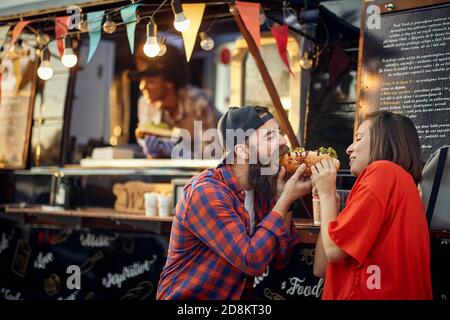 Cute kaukasischen Paar essen ein Sandwich zusammen vor Fast Food Stockfoto