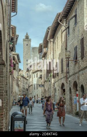 SAN GIMIGNANO, ITALIEN - september 20 2020: Stadtbild mit Menschen flanieren in der zentralen san Giovanni Straße mit berühmten Türmen im Hintergrund, sho Stockfoto