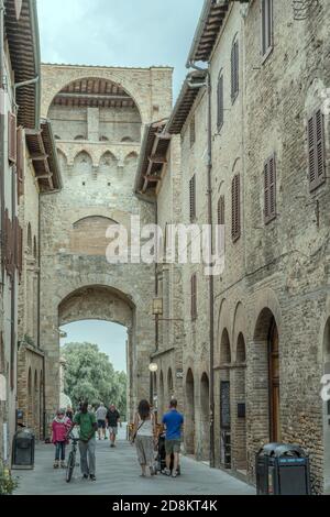 SAN GIMIGNANO, ITALIEN - september 20 2020: Stadtbild mit Menschen, die auf der Straße an der Innenseite der san Giovanni-Tür spazieren, in hellem Licht auf Septem geschossen Stockfoto