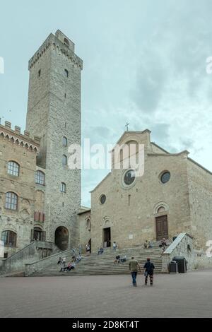 SAN GIMIGNANO, ITALIEN - september 20 2020: Stadtbild mit Spaziergängern und Ausruhen auf dem zentralen Collegiata-Platz, aufgenommen in hellem Licht am september Stockfoto