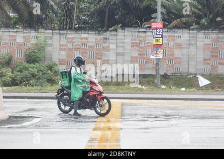 KUALA LUMPUR, MALAYSIA, 17. September 2019: Grabfood online bestellt wird auf dem Motorrad von Greifer geliefert, während regnerischer Tage. Grabfood ist ein Stockfoto