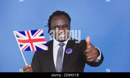 Junger afroamerikanischer schwarzer Mann mit britischer Flagge eu-Abzeichen und Daumen nach oben. Hochwertige Fotos Stockfoto