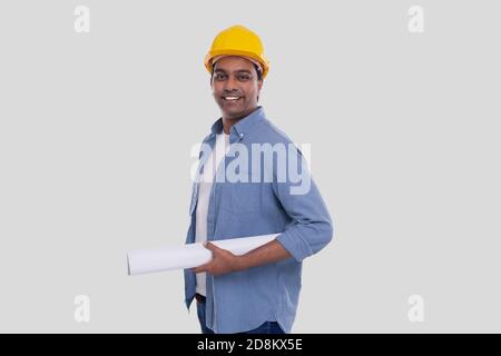 Bauarbeiter Holding House Plan in den Händen. Architect Holding Blueprints. Gelber Harthelm. Stockfoto