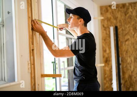 Ein hübscher junger Mann, der doppelte Schiebetür in der Terrasse installiert Eine neue Hausbaustelle Stockfoto