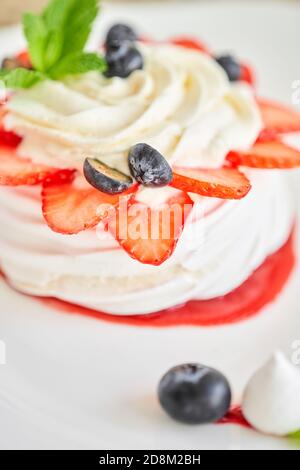 Pavlova ist ein Based-Based-Dessert mit einer knackigen Kruste gekrönt. Dekorierte Erdbeere, Minzblatt, Heidelbeere und Schlagsahne. Süßes Essen im Restaurant Stockfoto