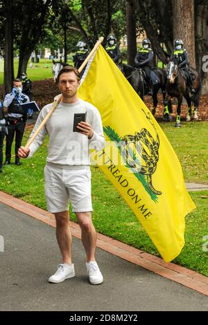 Melbourne, Australien 31 Oct 2020, ein männlicher Protestler mit einer „Tret nicht auf mich“-Flagge, wie steht mit seinem Telefon und vor Polizeipferden und Polizisten in Treasury Gardens, Melbourne. Kredit: Michael Currie/Alamy Live Nachrichten Stockfoto