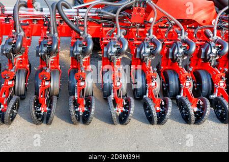 Rote moderne mehrreihige Sämaschine, Räder, Verteilerrohre und Arbeitsmechanismen der pneumatischen landwirtschaftlichen Sämaschine, Kopierer Raum. Stockfoto