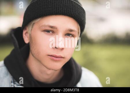 Stylish teen junge 15-16 Jahre alt trägt schwarz gestrickt Hut und Hoodie im Freien Nahaufnahme. Blick auf die Kamera. Herbstsaison. Teenagerhood. Stockfoto