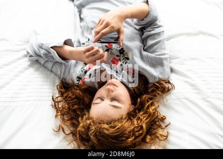 Ein rothaariges junges Teenager-Mädchen auf ihrem Bett Stockfoto