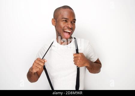 Portrait von fröhlichen jungen schwarzen Mann posiert mit Hosenträger von Weiße Wand Stockfoto