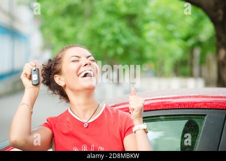 Habe gerade ein Auto gewonnen!!! Super aufgeregt lächelnd brünette lockig Mädchen Frau feiern Fahrer halten Schlüssel ihres neuen Auto Auto Auto draußen im Sommer Stockfoto