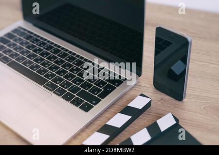 Movie Clapper Laptop und Smartphone auf dem Holztisch Stockfoto