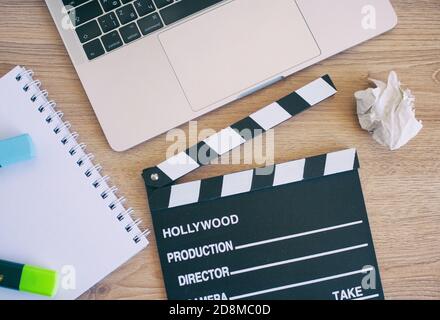 Videobearbeitung, Movie Clapper Laptop und Bleistift Notizblock auf dem Holz Tabellenansicht von oben Stockfoto