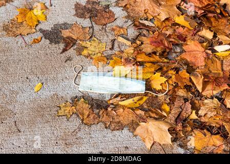 Quebec, Quebec, Kanada - 26. oktober 2020 : Covid-19 Schutzmaske auf dem Boden in der Mitte von toten Blättern geworfen. Stockfoto