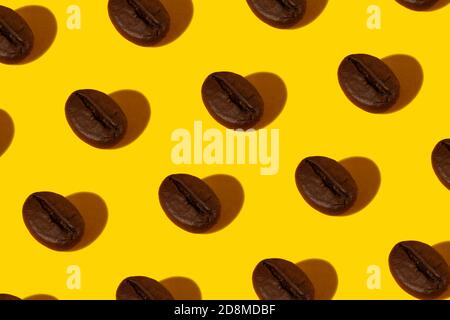 Kreative helle Collage aus echten Makrofotos ausgewählter Kaffeebohnen auf gelbem Hintergrund mit einem harten Schatten in Herzform. Stockfoto