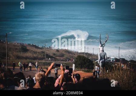 Menge auf Klippe am North Beach Wellen beeindruckende Welle und Wellen von mutigen Surfern, Portugal Stockfoto