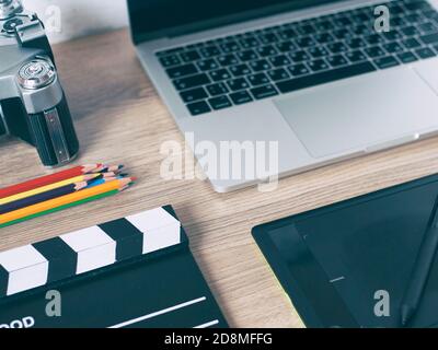 Büroschreibtisch mit Laptop-Computer, Smartphone, Pensil, Kamera und Filmklapper auf Holztisch Hintergrund. Stockfoto