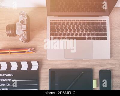 Büroschreibtisch mit Laptop-Computer, Smartphone, Pensil, Kamera und Filmklapper auf Holztisch Hintergrund. Stockfoto