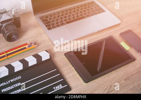 Büroschreibtisch mit Laptop-Computer, Smartphone, Pensil, Kamera und Filmklapper auf Holztisch Hintergrund. Stockfoto