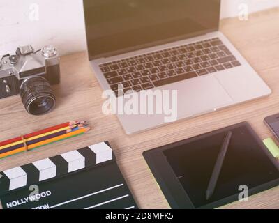 Büroschreibtisch mit Laptop-Computer, Smartphone, Pensil, Kamera und Filmklapper auf Holztisch Hintergrund. Stockfoto
