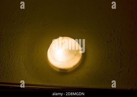 Helle runde einfache Lampe leuchtet auf raue grün verputzte Wand im Freien, kopieren Raum Hintergrund. Stockfoto