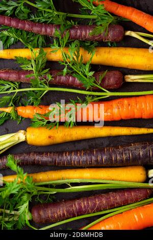 Overhead Ansicht von frischen Bio-bunten Karotten auf einem dunklen Oberfläche Stockfoto