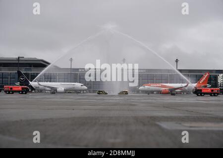 31. Oktober 2020, Berlin, Schönefeld: Nach der Landung stehen Flugzeuge der Airlines Lufthansa und Easyjet unter einem Wasserbrunnen der Flughafenfeuerwehr vor Terminal 1 des Hauptflughafens Berlin Brandenburg 'Willy Brandt' (BER). Nach einer langen Verspätung wird der Flughafen am 31.10.2020 eröffnet. Foto: Michael Kappeler/dpa Stockfoto