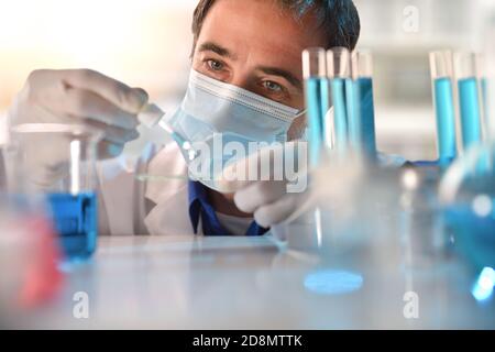 Detail des Laboranten, der blaue Flüssigkeit aus einer Pipette analysiert. Horizontale Zusammensetzung. Vorderansicht. Stockfoto