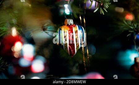 Ein Detail eines klassischen deutschen Weihnachtsbaums mit echten Kerzen und viel Lametta und einem herzförmigen Weihnachtsschmuck. Stockfoto