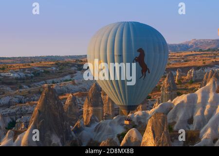 Heißluftballon, der zwischen Tufffelsen über dem Goreme-Tal in Kappadokien, Türkei, fliegt Stockfoto