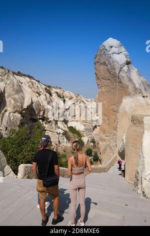 Touristen in der Nähe von riesigen Felsen in Goreme Open Air Museum mit Höhlenkirchen, Kappadokien, Türkei Stockfoto