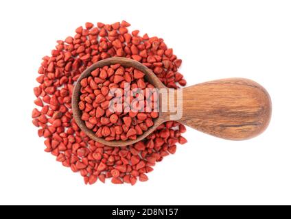 Annatto Samen in Holzlöffel, isoliert auf weißem Hintergrund. Achiote Samen, bixa orellana. Natürlicher Farbstoff zum Kochen und Essen. Draufsicht. Stockfoto