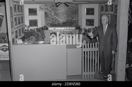 50er Jahre, historisch, ein Ausstellungsstand für die "First Assembly of God", W.13th & Madison, Eugene, Orgeon, USA. An der Wende des 20. Jahrhunderts, die etablierten Kirchen nicht begrüßen die pfingstwiederbelebung und so Menschen suchten ihre eigenen Orte der Anbetung und als diese Bewegung wuchs die Assemblies of God (AG) wurde gegründet, um zu schützen und zu bewahren die Pfingsttheogly durch Vereinigung durch kooperative Gemeinschaft. Ein lebensgroßer Ausschnitt oder Standee des männlichen Gründers der Kirche mit seiner Hand aus einladende Menschen kann im Bild gesehen werden. Stockfoto