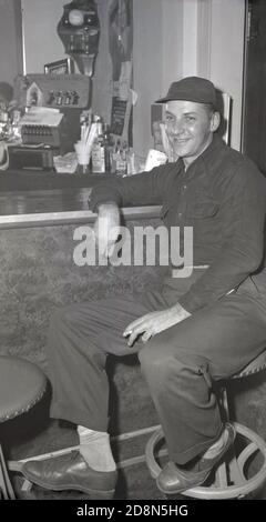 1950, historisch, ein männlicher Arbeiter, der sich nach der Arbeit auf einem Hocker in einer Bar entspannt, Eugene, Oregon, USA. Stockfoto