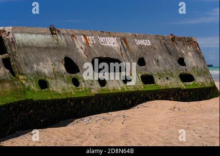 Eine gemalte Warnung verbietet den Zutritt zu diesem verfallenden Relikt des Zweiten Weltkriegs Juni 1944 ‘D-Day’ Landungen, die nur bei Ebbe am ‘Goldstrand’ in Arromanches-les-Bains, Calvados, Normandie, Frankreich zu Fuß erreicht werden. Die hier verbliebenen Lochbeton-Caissons waren Teil von Mulberry Harbour B, einem vorgefertigten Hafen, der aus England für die alliierte Invasion des nazibesetzten Frankreich geschleppt wurde. Wenn die Gezeiten steigen, füllen sich die Hohlbetonabschnitte wieder mit Meerwasser, mit der Gefahr, dass jemand darin eingeschlossen werden könnte. Der Hafen, vor der Küste montiert, wurde nach D-Day verwendet, um Millionen von Truppen, Fahrzeugen und Vorräten zu landen. Stockfoto