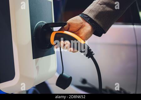 Farbbild der Hand eines Mannes, die Vorbereitung auf ein Elektroauto aufladen. Stockfoto