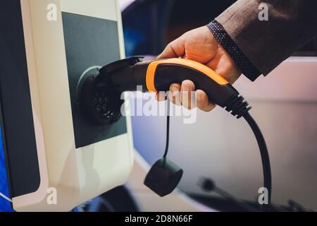 Farbbild der Hand eines Mannes, die Vorbereitung auf ein Elektroauto aufladen. Stockfoto